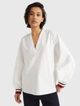 Blusa de manga larga Tommy Hilfiger confeccionada en algodón orgánico. Presenta un cuello en V amplio y puños elásticos con el diseño de rayas distintivo de la marca en colores blanco, rojo y azul marino.