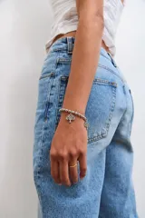 Pulsera de acero plateada compuesta por cuentas esféricas y un dije colgante en forma de árbol de la vida.