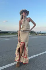 Falda midi color beige confeccionada en lino, con corte irregular, volados y ribete rojo.