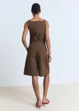 Short de corte recto y tiro medio, confeccionado en algodón color marrón. Presenta diseño con pinzas frontales, bolsillos laterales y bolsillos de ribete en la parte posterior. Cuenta con cierre oculto de botón, gancho y cremallera.