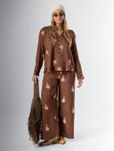 Conjunto de camisa y pantalón marrón chocolate con bordados en hilo crudo. El pantalón lleva elástico en la cintura.