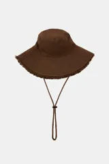 Gorro tipo bucket marrón de 100% algodón, con ala ancha con pespuntes y acabado deshilachado. Incluye cordón ajustable con stopper.
