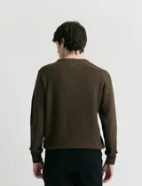 Sweater de punto con textura en color verde oscuro, de cuello redondo y manga larga.