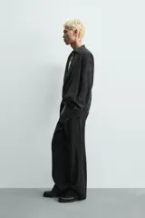 Camisa de corte relajado confeccionada en tejido fluido con mezcla de viscosa y lyocell. Presenta cuello polo, manga larga con puños abotonados y un diseño cruzado con cierre frontal de botones.
