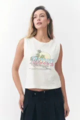 Musculosa Roxy color crudo, con cuello redondo y diseño sin mangas con sisas amplias. Presenta un estampado frontal con la palabra 'Roxy' en tonos degradados de rosado y celeste, acompañado de palmeras, un sol y la leyenda 'Sunsets Chaser'.