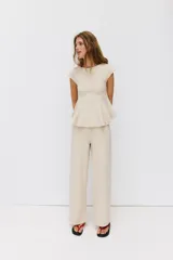Top blanco de piqué con cuello redondo y mangas cortas, de corte entallado en la cintura y bajo redondeado con acabado en peplum.