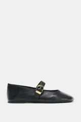 Zapatos tipo bailarina en piel color negro, con tira delantera y hebilla metálica dorada ajustable, terminación en punta redonda y suela plana.