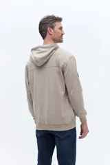 Canguro con capucha de algodón color beige, con cordones de ajuste y estampa circular frontal con el nombre de la marca y el año 1971.