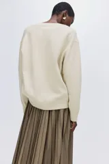 Buzo oversized de punto suave, con cuello en V, hombros caídos y terminaciones acanaladas en cuello, puños y bajo.