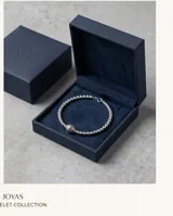 Pulsera de plata italiana 925 compuesta por esferas pequeñas, con un dije central esférico de mayor tamaño flanqueado por dos piezas decorativas con detalles labrados.