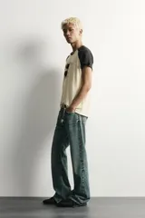 Camiseta regular fit de corte clásico con efecto lavado, cuello redondo negro y mangas cortas ranglán negras. El cuerpo es de color blanco con estampa frontal inspirada en automovilismo con el texto "Asphalt Speed".
