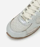 Championes de estilo urbano inspirados en botines de fútbol, confeccionados en poliuretano plateado con paneles de malla transpirable. Presentan cierre con cordones, punta redondeada y suela plana de goma en color marrón.
