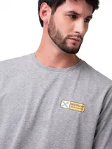 Remera de manga corta y cuello redondo color gris jaspeado. Presenta un pequeño logo estampado en el lado izquierdo del pecho y un diseño gráfico de mayor tamaño en la espalda.