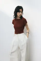 Top marrón de punto suave con mangas japonesas, corte entallado, cuello redondo y frunces laterales que crean un efecto drapeado.