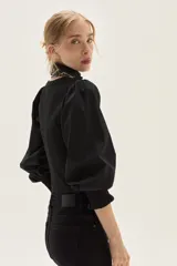 Top de calce ajustado color marrón, con escote cuadrado y mangas largas abullonadas de tela lisa. Los puños de las mangas son elastizados.