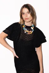 Vestido largo negro de encaje transparente con diseño geométrico, mangas cortas con volados y cuello alto.
