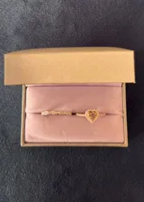 Set de dos anillos de plata 925 con acabado brillante. El primer anillo presenta un diseño entrelazado con pequeñas incrustaciones de zirconias, mientras que el segundo anillo destaca por un dije central en forma de corazón con una piedra amarilla y borde de zirconias.