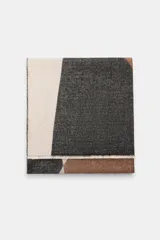 Pañuelo rectangular con diseño color block en tonos beige, gris oscuro y marrón. Presenta una textura tejida y acabados deshilachados en los bordes.