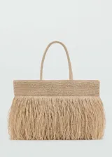 Bolso shopper grande de tejido de fibra natural color beige, con doble asa superior y detalle de flecos en la parte frontal. Cuenta con cierre de botón magnético y bolsillo interior.