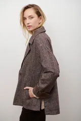 Chaquetón de lana color bordó con diseño de espiga y motas blancas. Tiene solapa, doble abotonadura frontal, mangas largas con detalle de correa y hebilla en los puños.