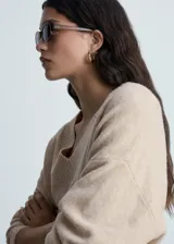 Jersey de punto medio con cuello en pico y terminaciones de canalé en puños y bajo. Presenta un diseño recto y oversize de manga larga.