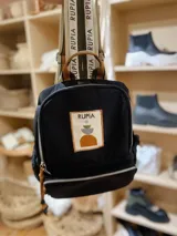 Mochila de nylon color negro con cierre frontal, correas ajustables estampadas con el nombre de la marca y parche bordado decorativo en el frente.