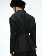 Blazer de corte sastrero con diseño de doble botonadura y solapas clásicas. Presenta un patrón de rayas verticales finas, hombros estructurados y bolsillos con solapa en la parte frontal.