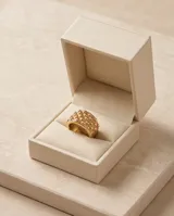 Anillo ancho de acero con baño de oro, con diseño de textura punteada en relieve.