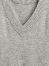 Buzo de punto con cuello en V, manga larga y puños acanalados. Diseño holgado y minimalista.