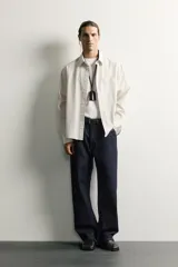 Camisa relaxed fit de algodón con estructura, cuello solapa, manga larga con puño abotonado, bolsillo de parche en el pecho y cierre frontal con botones. Presenta diseño de rayas finas.