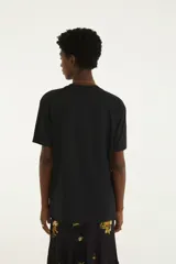 Remera Farm Rio de color negro con cuello redondo y mangas cortas. Presenta un estampado frontal con la inscripción de la marca, un tranvía rodeado de vegetación, animales y elementos tropicales.