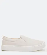 Championes slip-on color beige, sin cordones, con diseño capitoné en la parte frontal y suela blanca de goma.