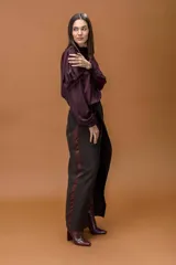 Blusa de tela satinada color violeta oscuro, con cuello drapeado amplio y mangas largas con puños elásticos.