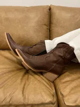 Bota de caña media baja realizada en cuero engrasado color negro, con detalle de punta fina y taco de 5 cm. El interior está forrado en forrería vacuna y el fondo es de madera.