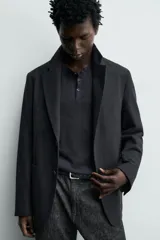 Blazer relaxed fit de estructura color gris, confeccionado en tejido con algodón, cuello con solapas de muesca, manga larga con botones en los puños y bolsillos de plastrón en la cadera.