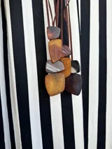 Collar de largo regulable con cordón de cuero y dos piezas colgantes de resina en tonos tierra y marmolados.