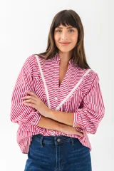 Camisa a rayas verticales rojas y blancas con cuello mao y mangas 3/4 abullonadas. Presenta detalles de puntilla blanca en el canesú. Cierre frontal con botones.