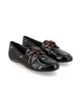 Mocasín plano de mujer color negro charol, estilo náutico, con cordones marrones y ojales metálicos dorados.