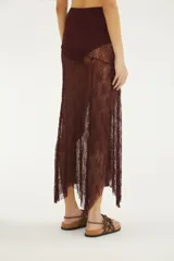 Falda larga bordó de encaje translúcido, de tiro alto y diseño asimétrico con bajo puntiagudo. Incluye hot pants interiores.