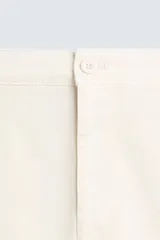 Pantalón chino de corte ajustado, color beige, con bolsillos laterales y bolsillos traseros de vivo. Cuenta con cierre frontal de cremallera y botón.