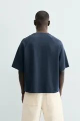 Camiseta de manga corta, cuello redondo y calce relajado, confeccionada en tejido con estructura waffle de color azul marino. Presenta estampados y bordados combinados a contraste en el delantero con texto en blanco.