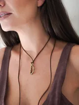 Collar de tiento de cuero marrón con dije en forma de letra y placa metálica con la inscripción de la marca.