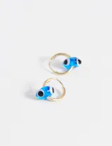 Aros de tipo argolla dorada con dije colgante de cuenta de vidrio en forma de ojo turco color azul, blanco y negro.