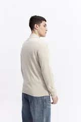Campera tejida de algodón en color beige, con cierre frontal completo, cuello levemente elevado y puños y ruedo acanalados. Presenta un pequeño logo bordado en el pecho.
