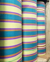 Bolso tipo tote grande con estampado a rayas verticales en tonos celeste, blanco y bordó. Tiene doble asa corta de mano y cierre superior.