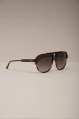 Lentes de sol estilo aviador con montura gruesa de acetato con patrón carey en tonos verde oliva y negro. Lentes oscuros con degradado gris.