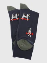 Calcetines largos de color azul marino con diseño estampado de perros de raza Jack Russell Terrier realizando acrobacias en monopatín (skateboard) con detalles en rojo y blanco. El talón y la punta son de color verde oliva.
