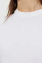 Remera blanca de algodón con corte boxy, ligeramente oversize, de líneas rectas y mangas cortas, con cuello redondo acanalado.