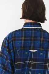 Camisa de corte holgado en color bordó con estampado de cuadros y monograma. Presenta cuello redondo con borde de puntilla, bolsillo frontal con detalle de puntilla, cierre frontal con botones y puños con terminación en puntilla.