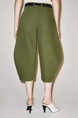Jeans capri de tiro medio y corte balloon leg en color verde militar. Presenta trabillas en la cintura, bolsillos laterales y bolsillos de plastrón tipo cargo en las piernas. Cuenta con cierre frontal con cremallera y botón metálico.